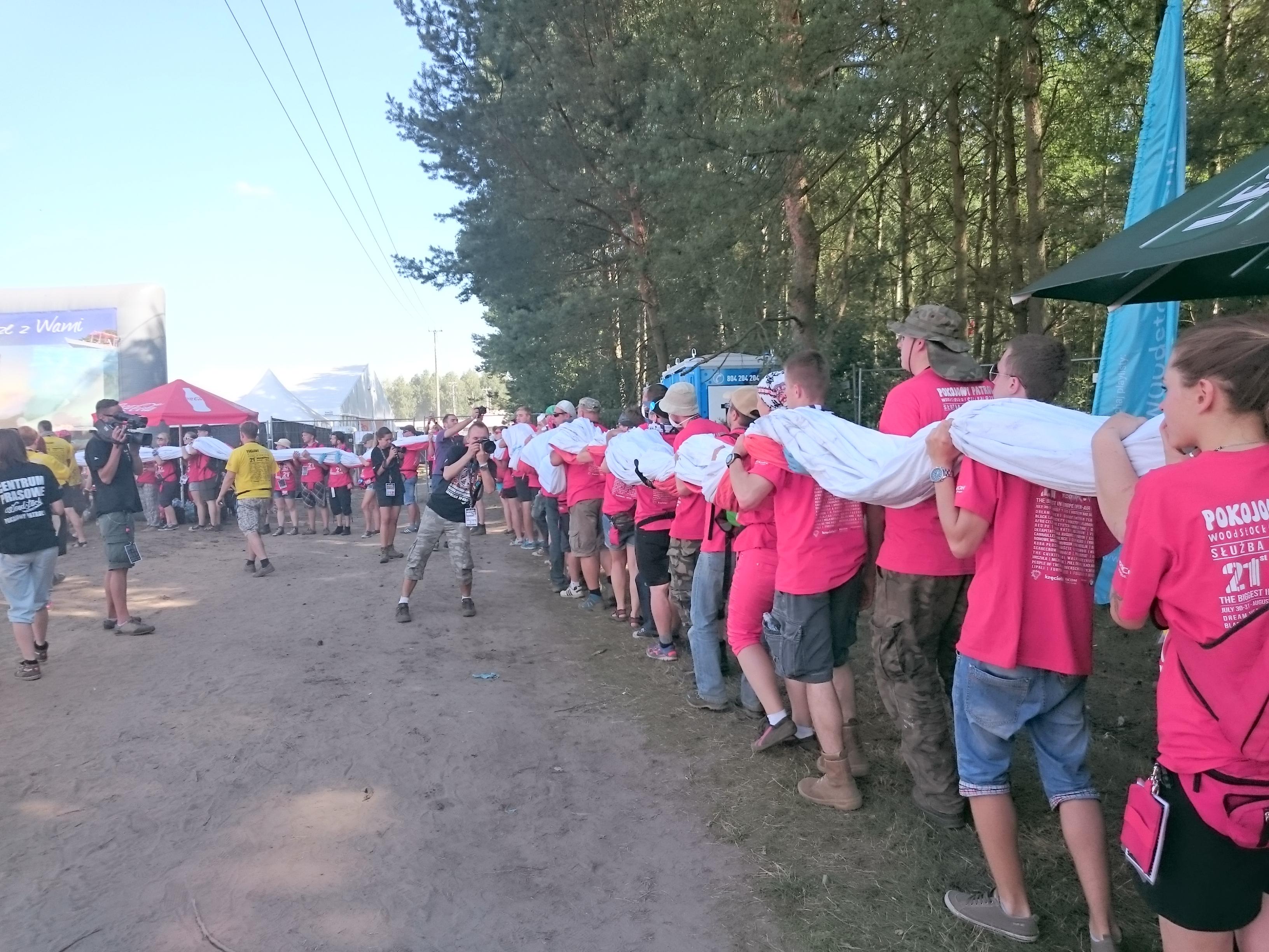 Przygotowania do Godziny "W" na Woodstocku - wolontariusze niosą gigantyczną polską flagę, która z inicjatywy Tomasza Zimocha powstała na Euro 2012. Flaga ma być rozwinięta na woodstockowym polu o 17.00
